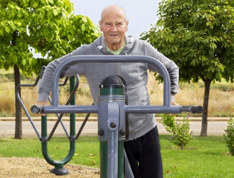 old man  training  with  fitness equipment in public outdoor gym