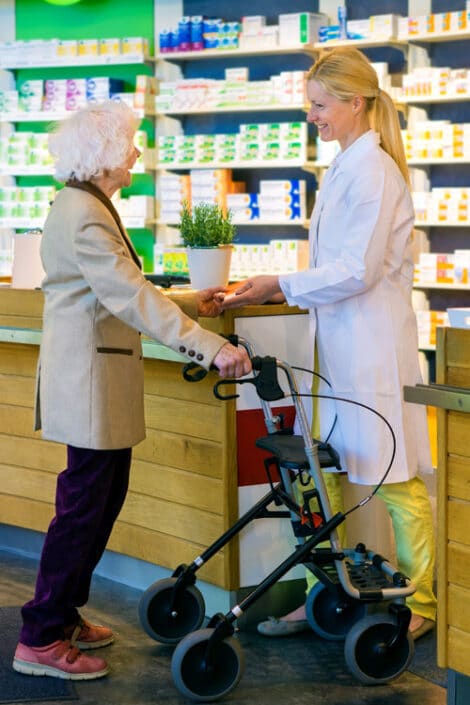 Elderly customer using walker with pharmacist.