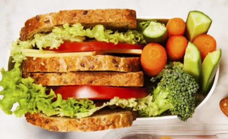 Healthy lunch box with sandwich and fresh vegetables, bottle of